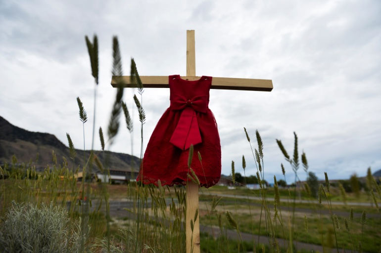 el vestido rojo de un niño cuelga de una estaca cerca de los terrenos donde se encontraron tumbas sin marcar
